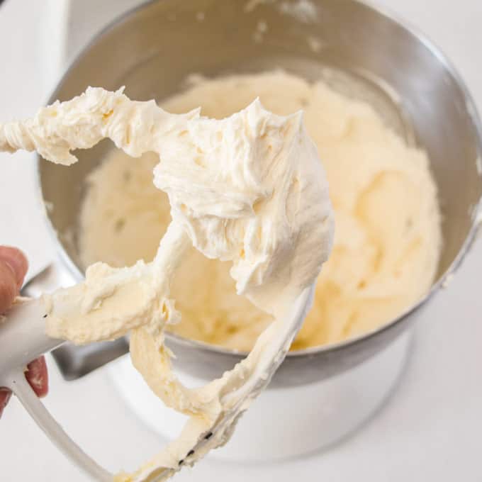 A paddle from a stand mixer covered in white buttercream.