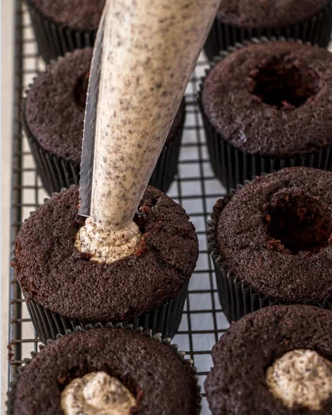 Filling chocolate cupcakes with a cookies and cream filling using a piping bag