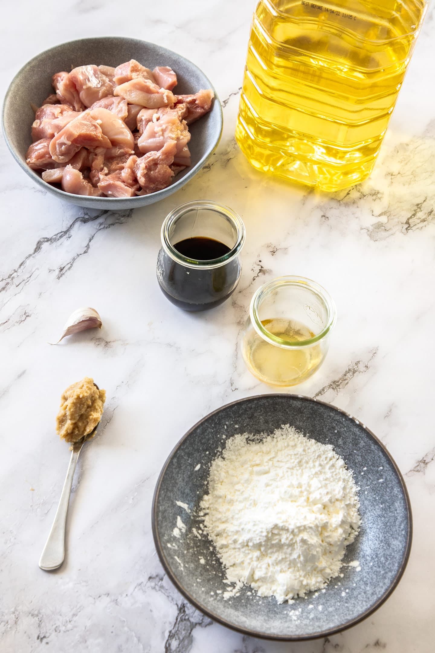 Ingredients for karaage chicken laid out on a marble surface.