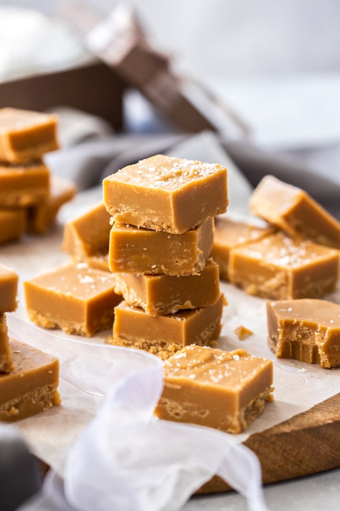 A stack of 4 pieces of salted caramel fudge on a wooden board.