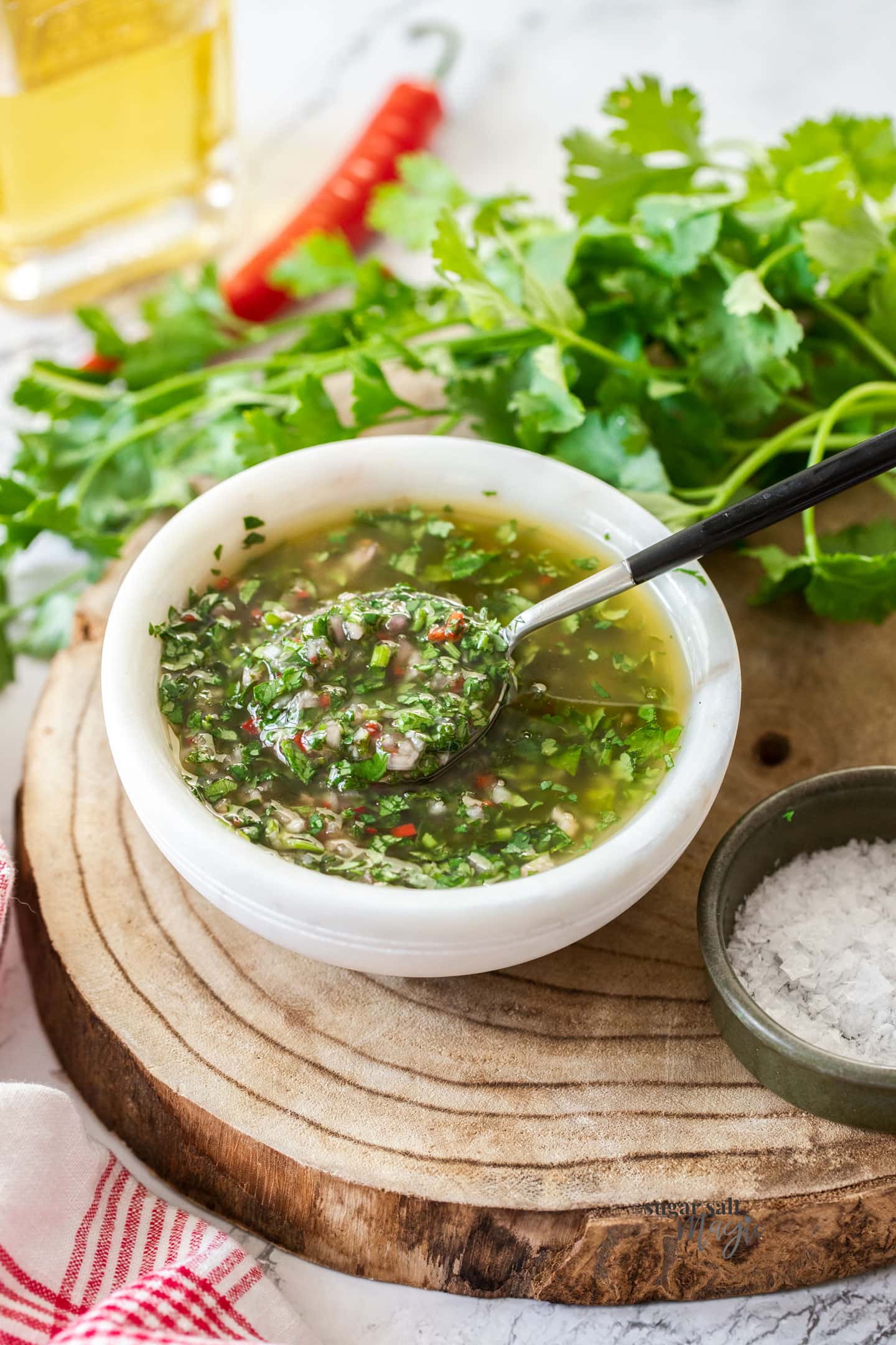 A bowl filled with herb sauce with a spoon dipping in.