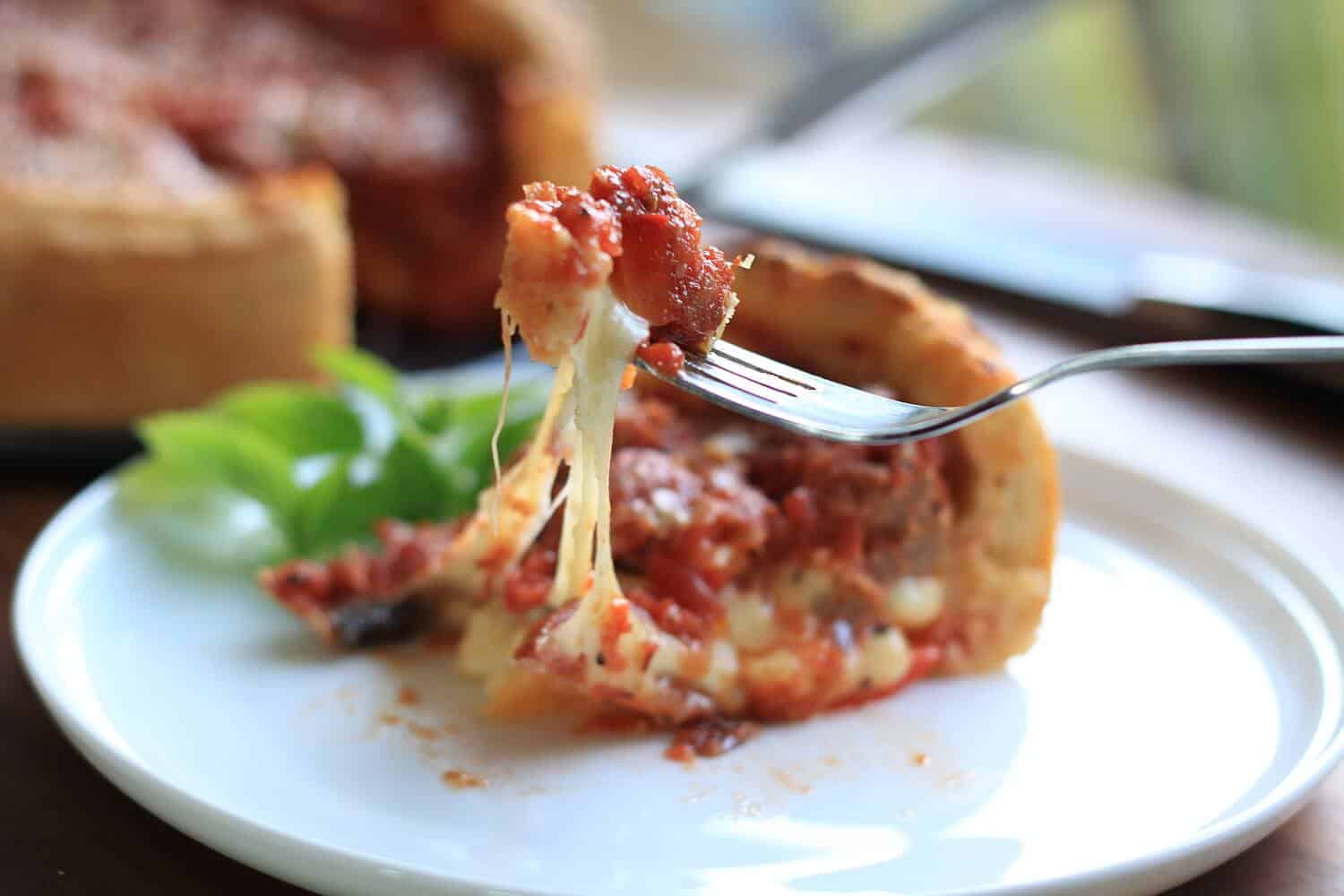 A fork taking a piece of deep dish pizza.