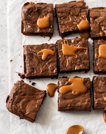 9 brownies on a white baking paper with caramel drizzle over them