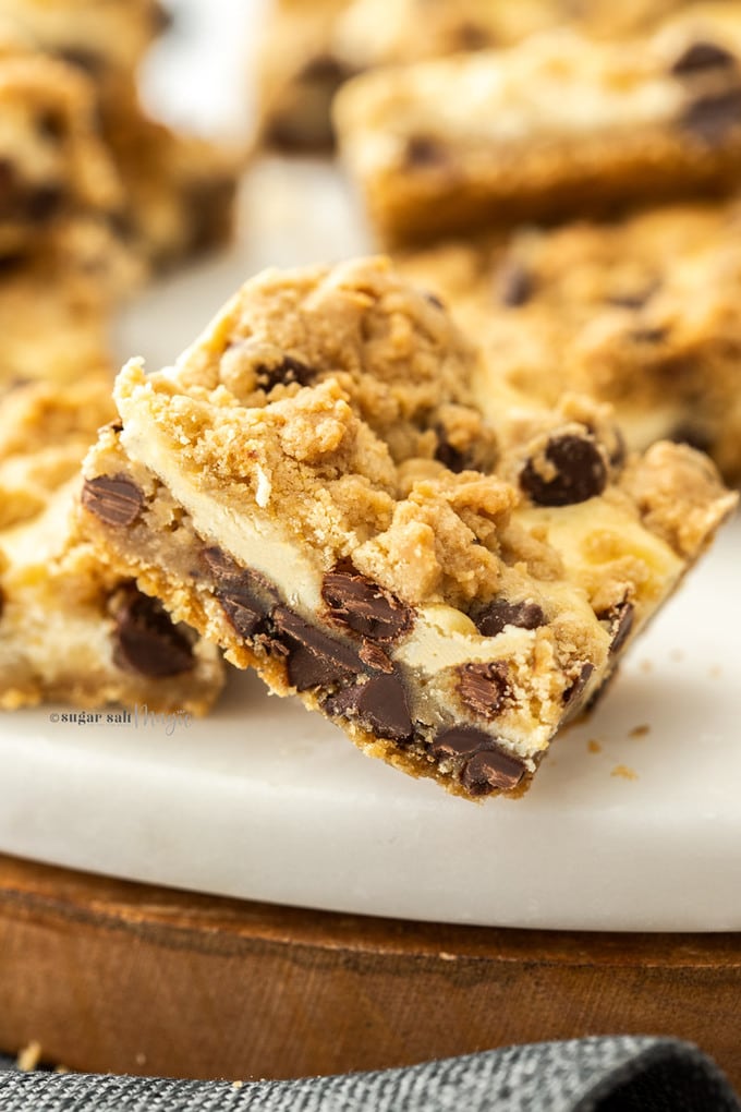 Closeup of a chocolate chip cheesecake bar on a white marble platter