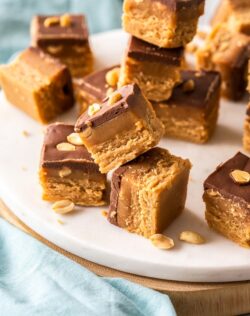 Pieces of caramel peanut fudge stacked up on a white platter