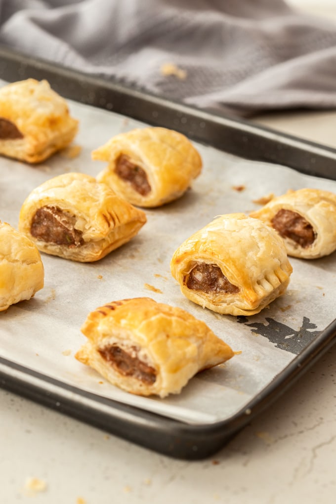 Freshly baked sausage rolls on a baking tray.
