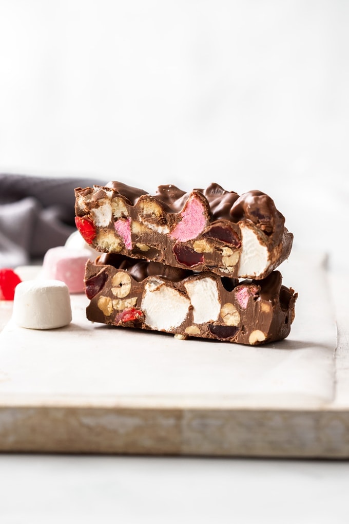 Slices of rocky road on a white board surrounded by marshmallows and candy.