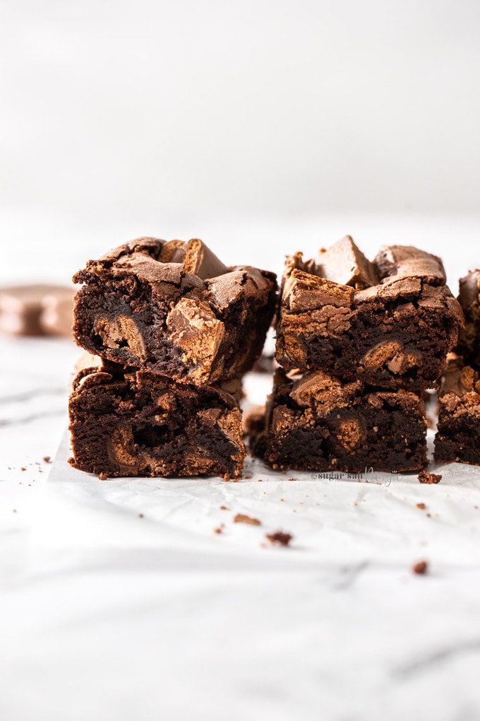 Two stacks of brownies sitting on a sheet of baking paper