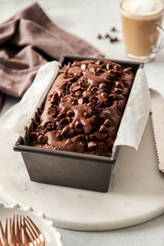 Chocolate Bread in a loaf tin sitting on a marble platter.