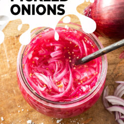 Bright pink onions in a glass jar on a wooden board