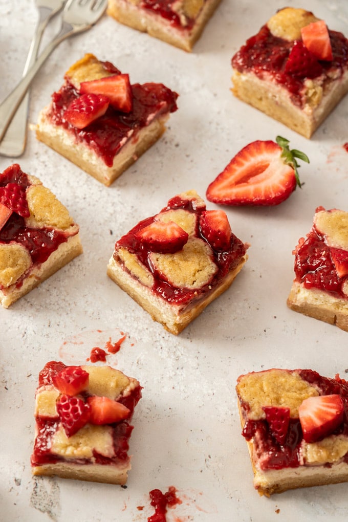Several squares of strawberry cheesecake bar sitting on a concrete surface