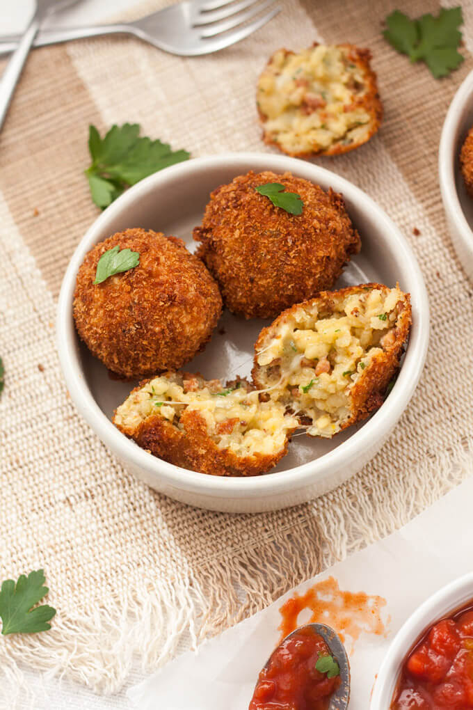 Arancini rice balls in a small dish with one broken open.