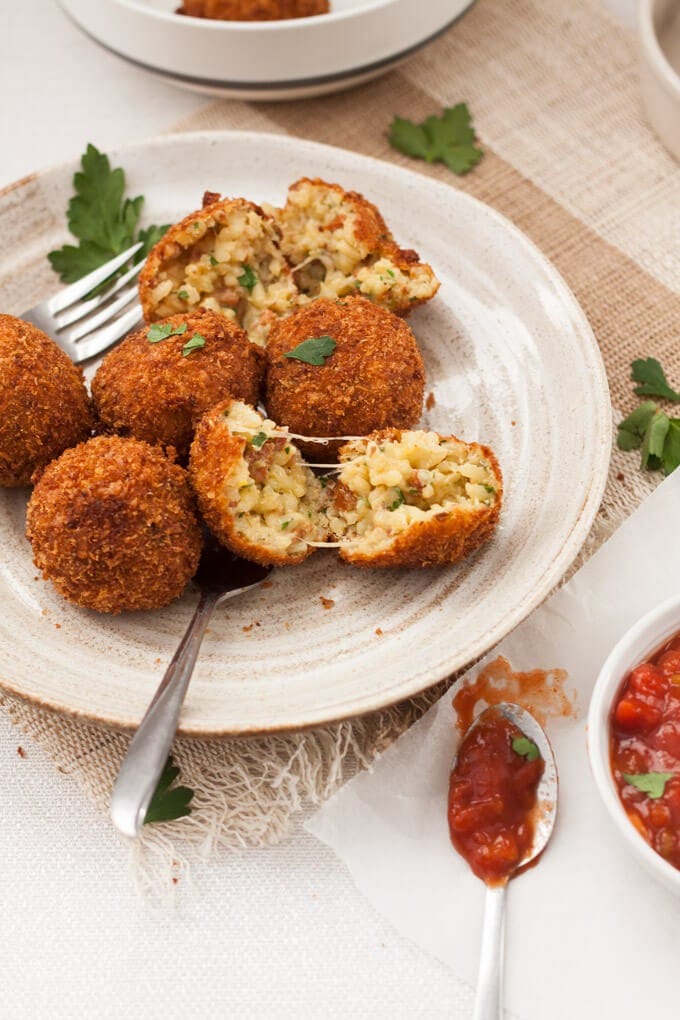 A plate with 6 arancini and 2 forks.
