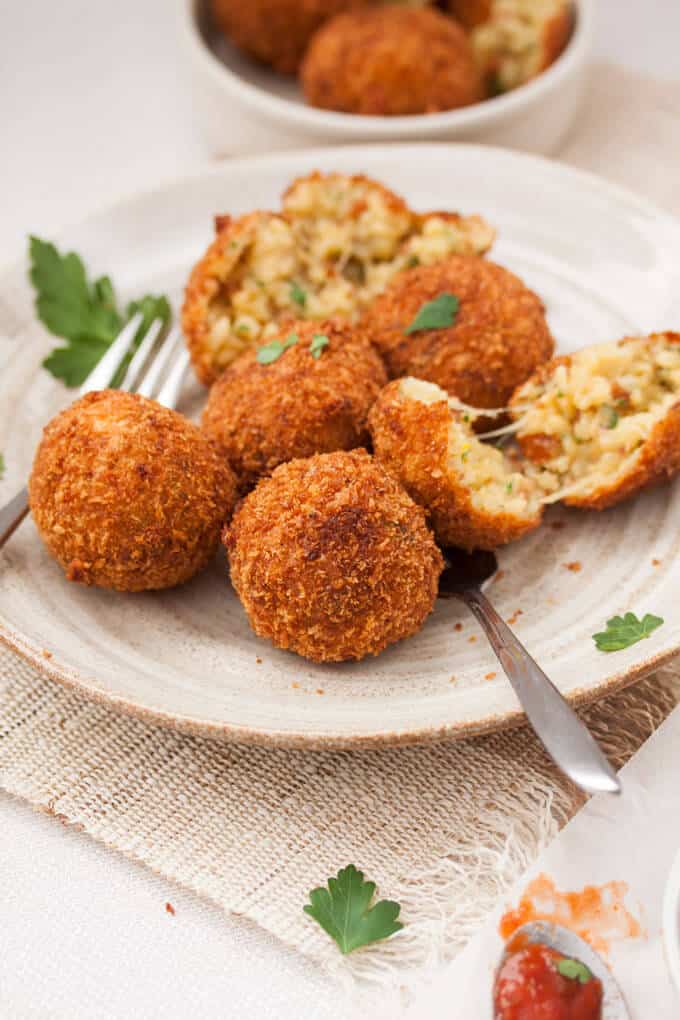 A group of arancini balls on a plate with forks.