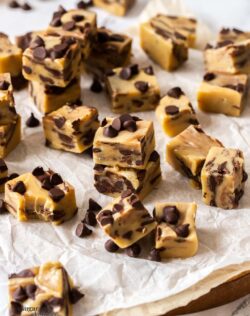 Squares of chocolate chip fudge on a sheet of baking paper