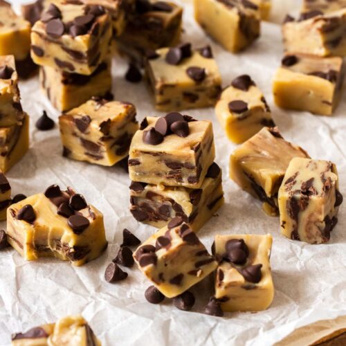 Squares of chocolate chip fudge on a sheet of baking paper