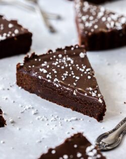Closeup of a slice of chocolate brownie tart with more pieces around it
