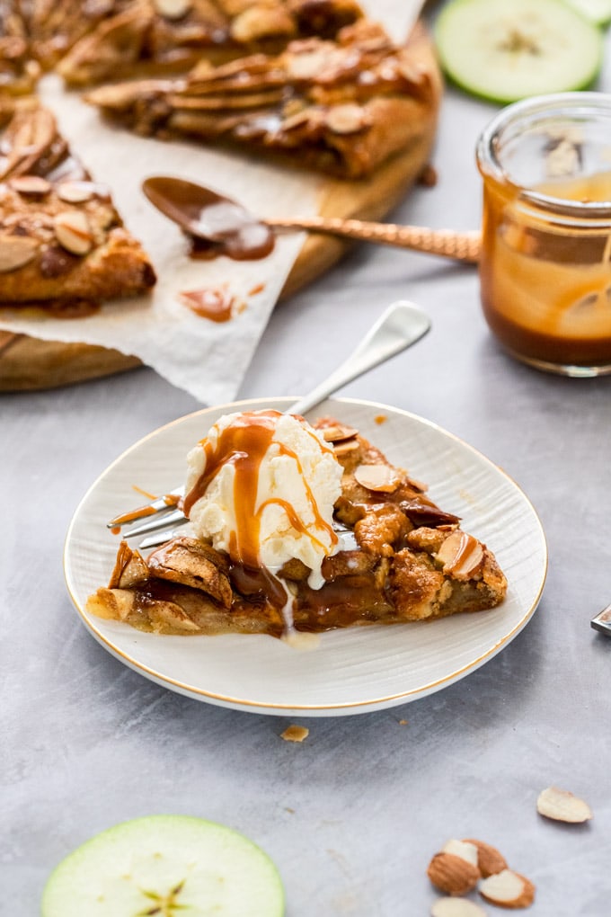 Slice of apple crostata on a white plate topped with caramel sauce 
