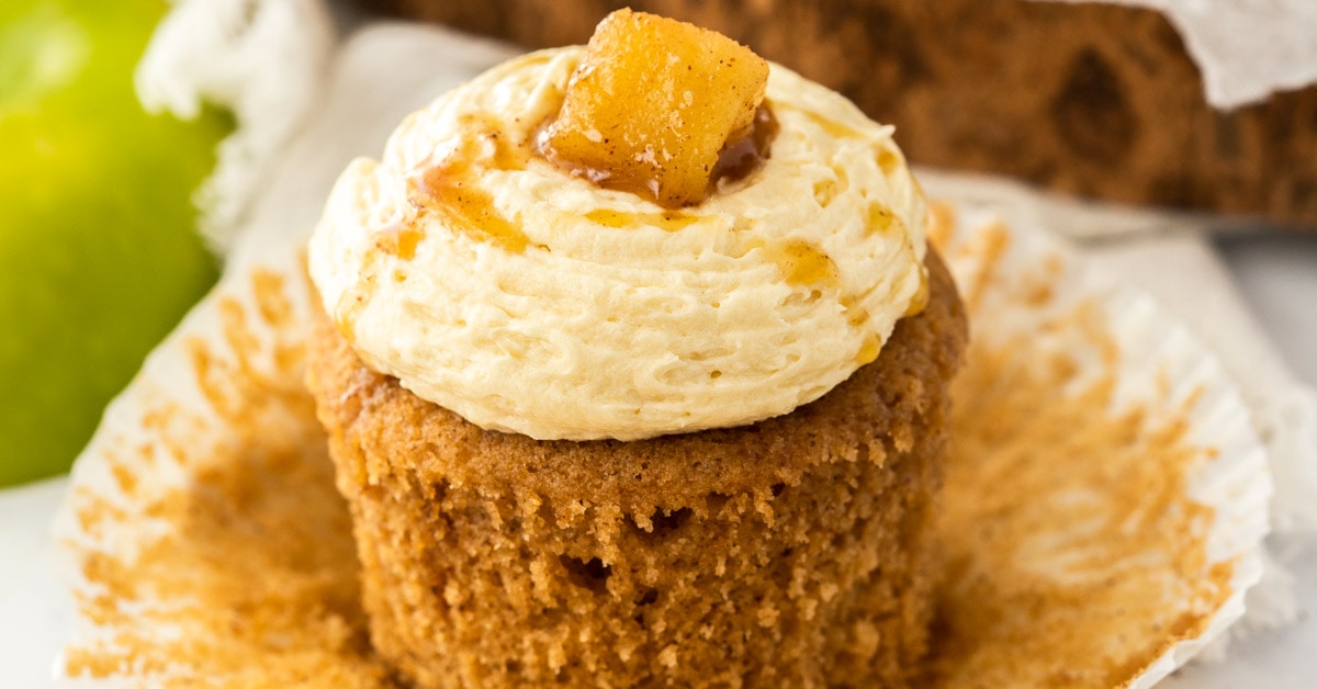 A closeup of an apple pie cupcake with the paper peeled away showing the texture of the cake.