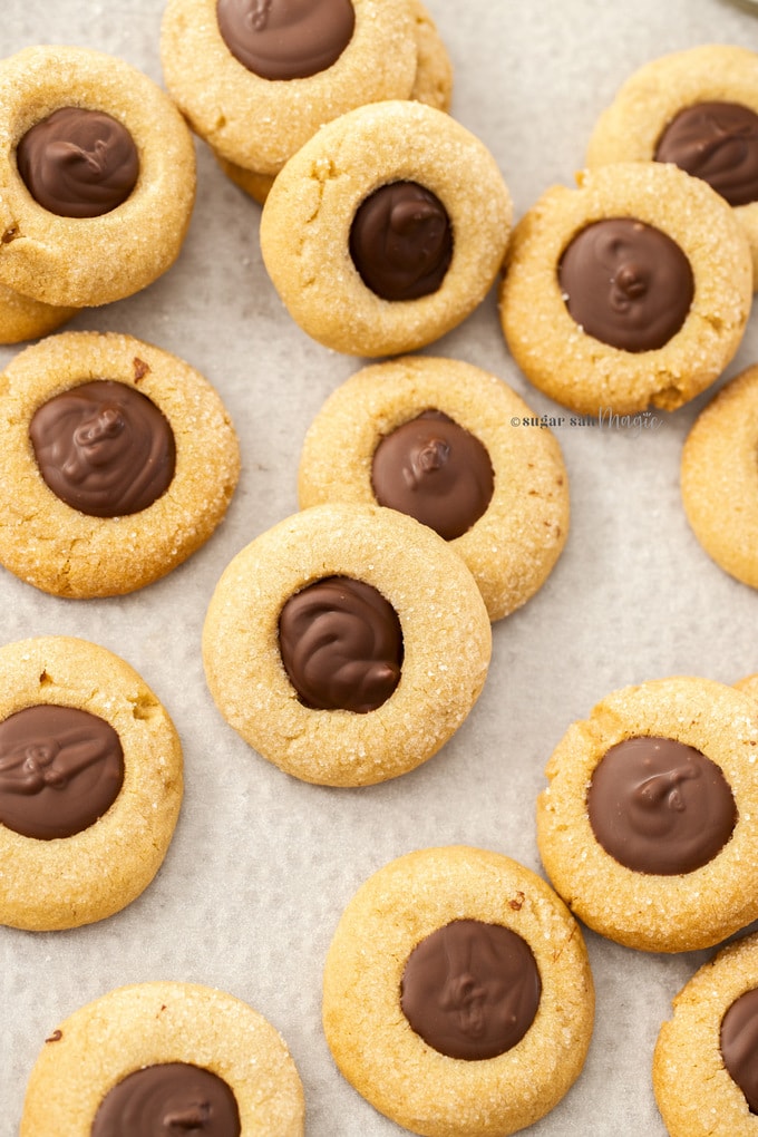 A batch of cookies with chocolate centres on a sheet of baking paper