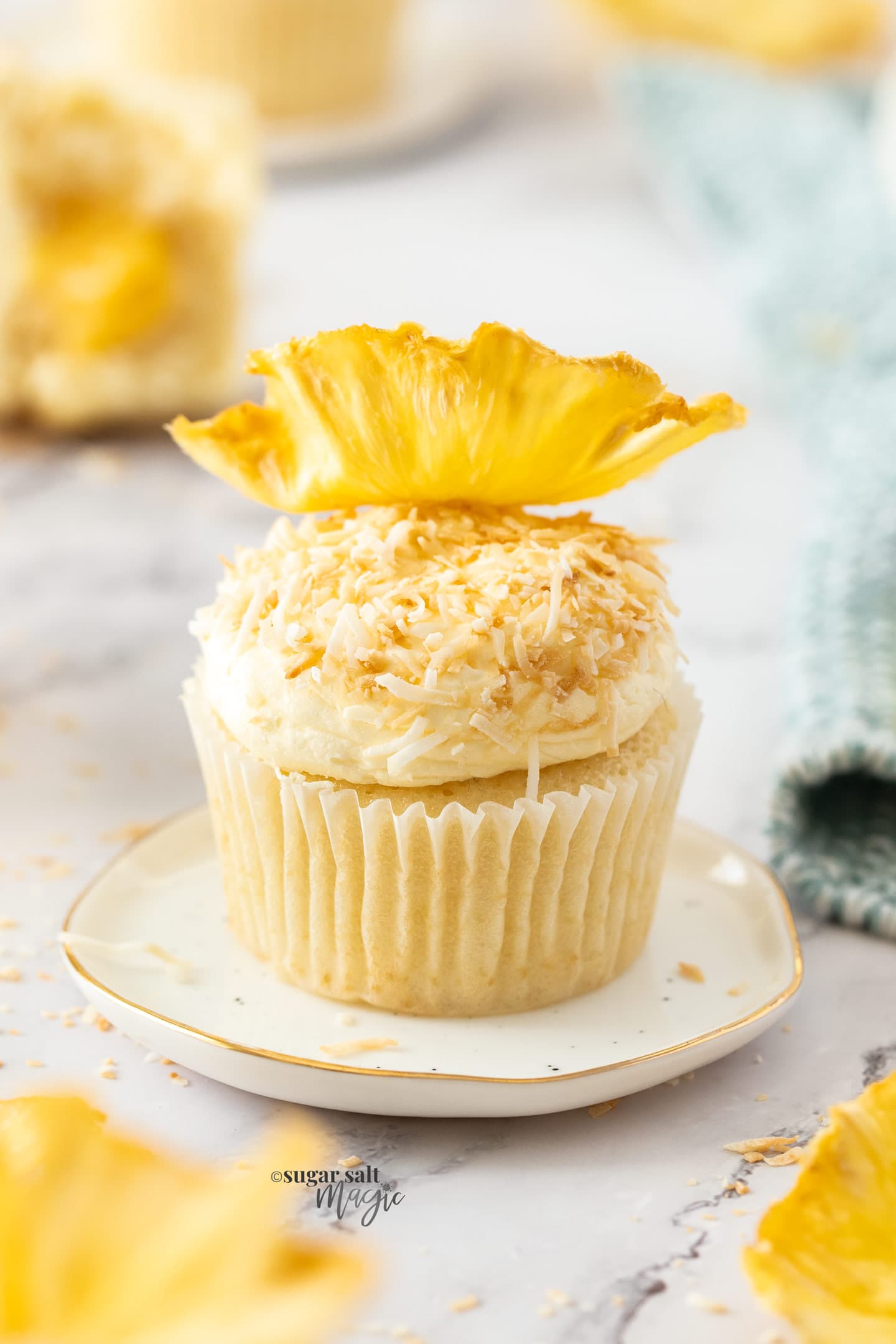 Closeup of a cupcake coated with coconut and topped with pineapple