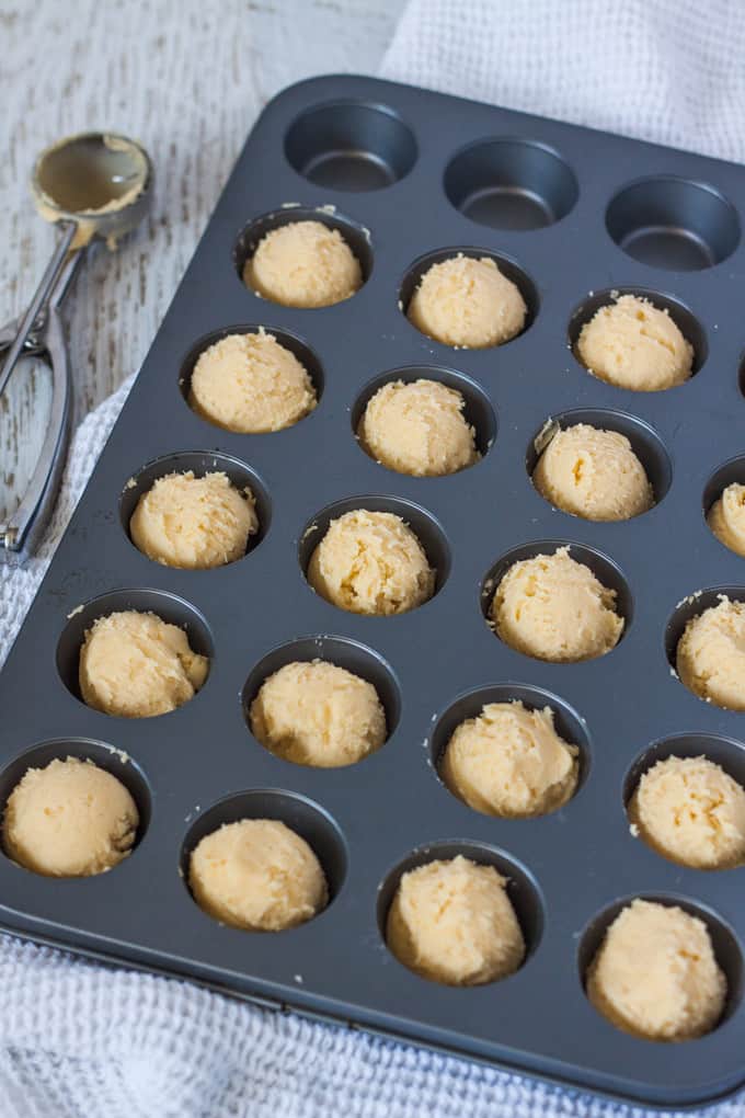 Shortbread cookie dough in the holes of a mini muffin tin