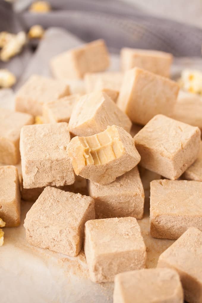 A pile of butter popcorn fudge with a bite taken out of one piece.