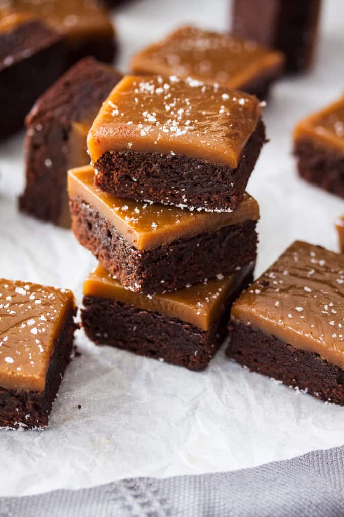 A stack of 3 chocolate brownies with caramel on top.