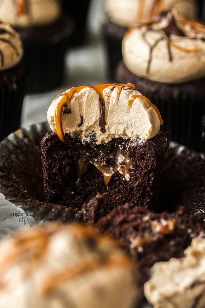 A closeup of inside a chocolate cupcake with caramel oozing out and caramel buttercream on top.