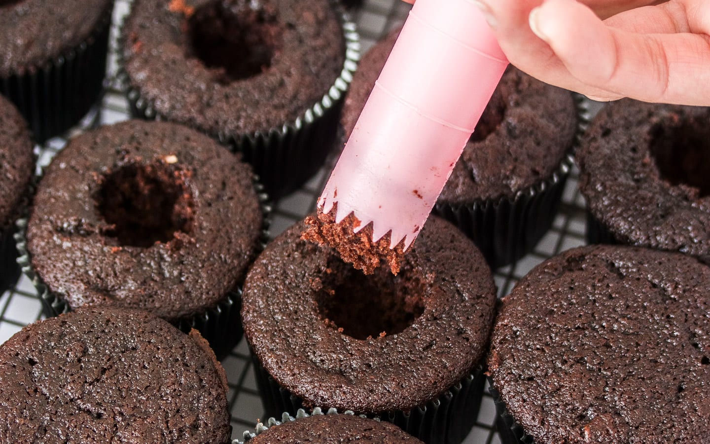Cutting the core out of the cupcake using a pink cupcake corer.