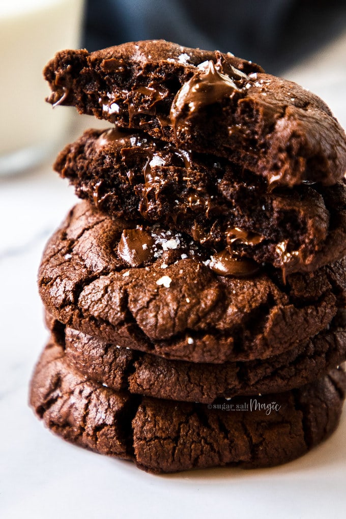 Closeup of a stack of chocolate cookies with the top one broken in half showing a fudgy centre