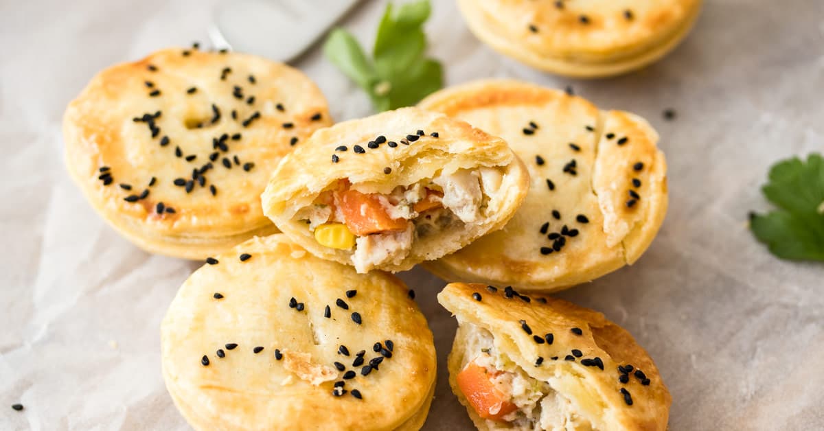 A pile of Mini Chicken Pot Pies, some are broken open to show the filling inside.