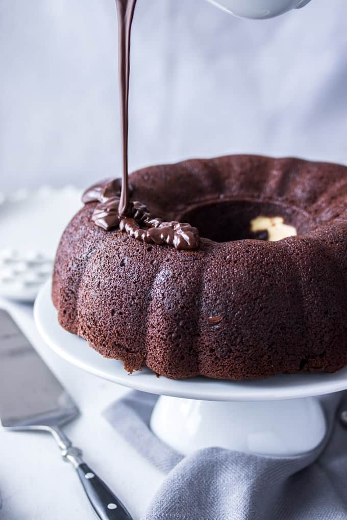 Chocolate ganache is drizzled on top of a chocolate bundt cake.