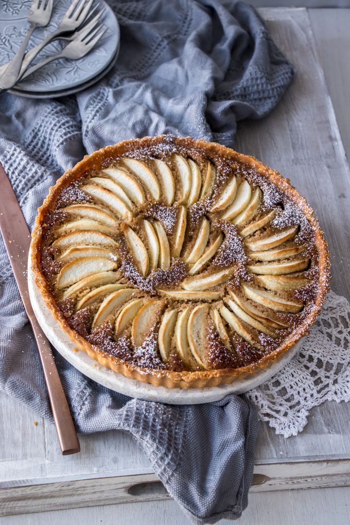 A fully baked Apple Frangipane Tart with powdered sugar on top.