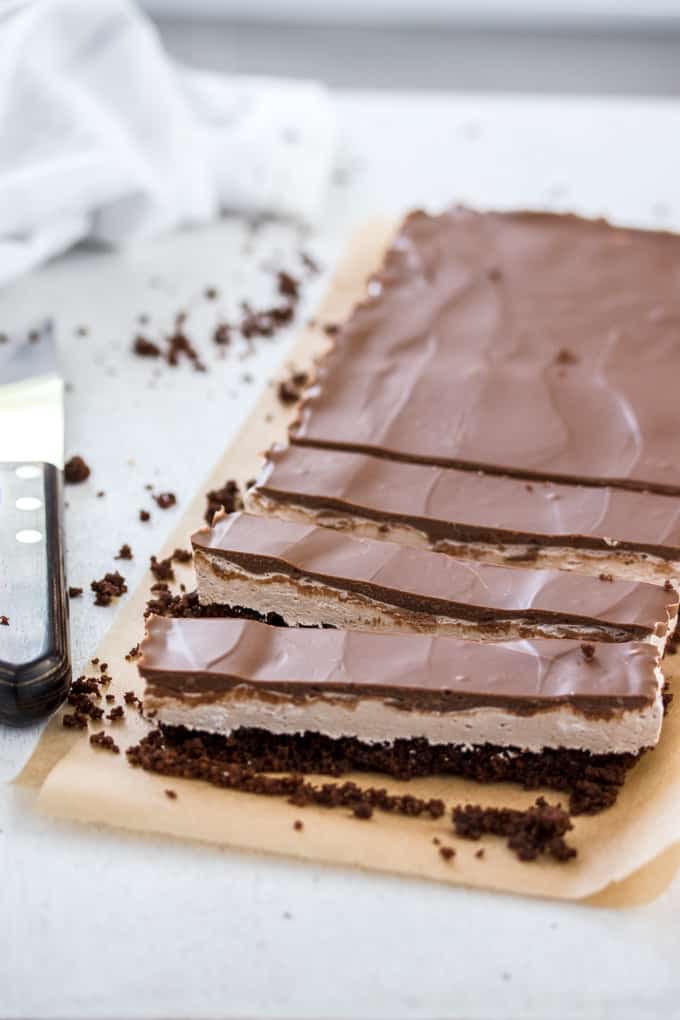 A Chocolate Malt Whipped Nougat Tart on a brown baking paper, half of it is sliced into bars.