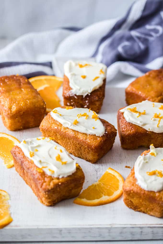 7 Mini Flourless Ginger Orange Cakes on a white board with slices of orange around.
