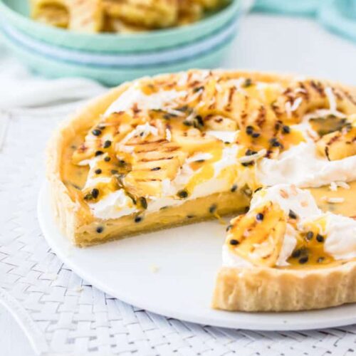 This Passionfruit Tart is a simple passionfruit curd custard filling in a crisp tart shell. It's all topped with grilled pineapple slices and coconut. Tropical tart heaven.