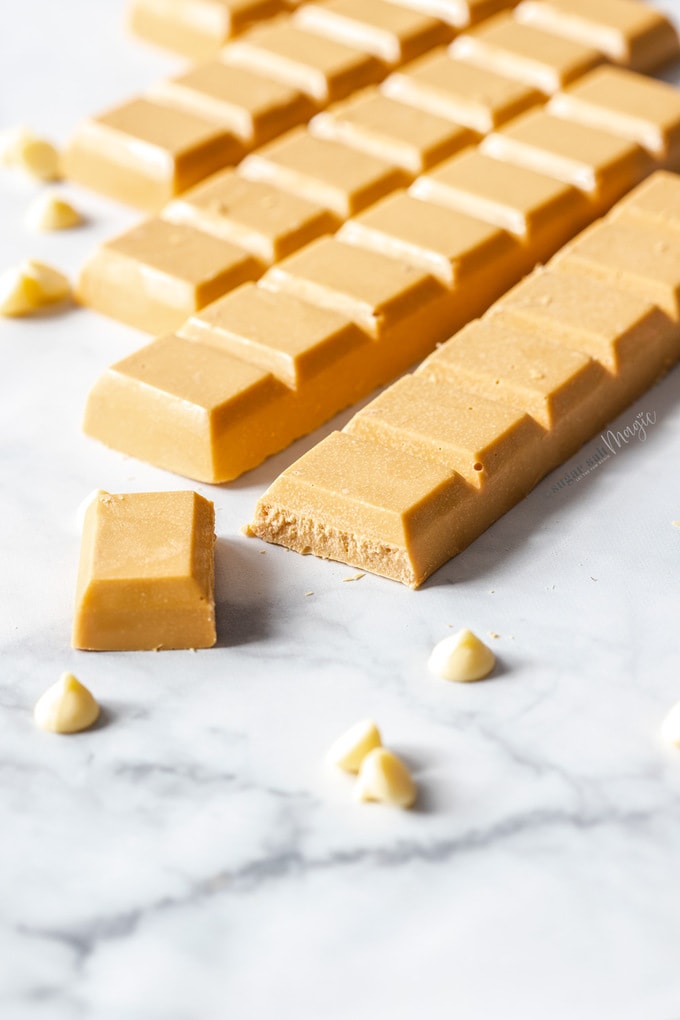 Bars of caramelised white chocolate on a marble surface, surrounded by white chocolate chips.