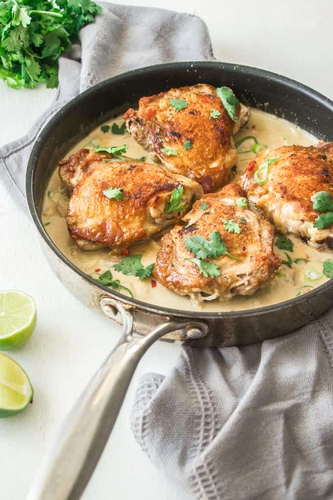 4 pieces of chicken thighs in a skillet with creamy sauce.