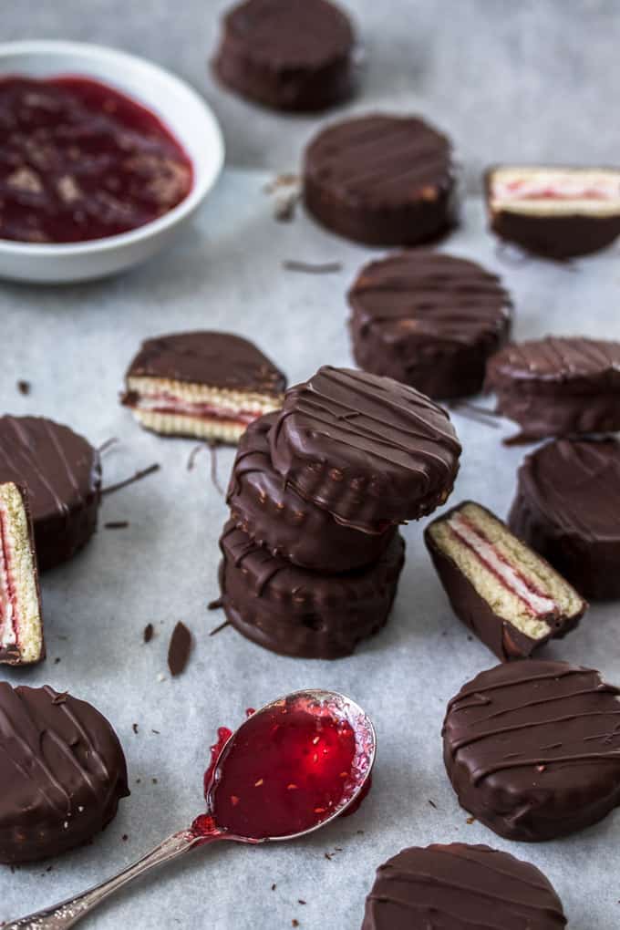 A stack of 3 mini wagon wheels with more scattered around next to a spoon of jam