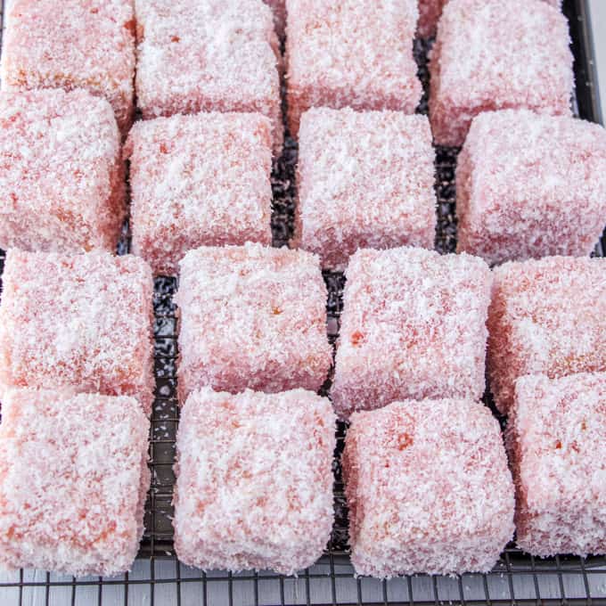 Rose Strawberry Lamingtons resting on a wire rack