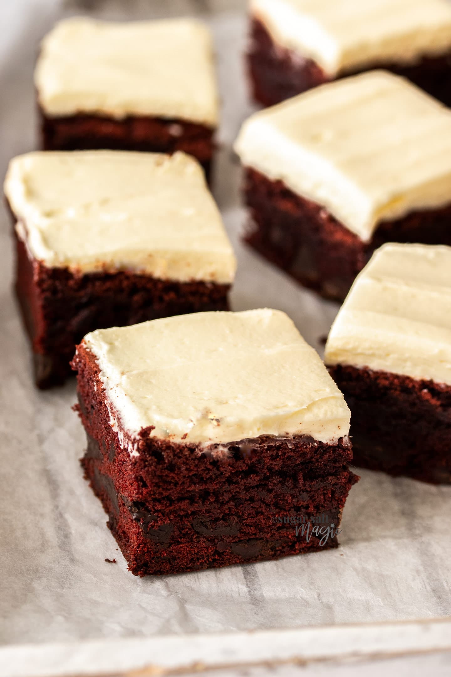 Closeup of 5 red velvet brownies on a sheet of baking paper.