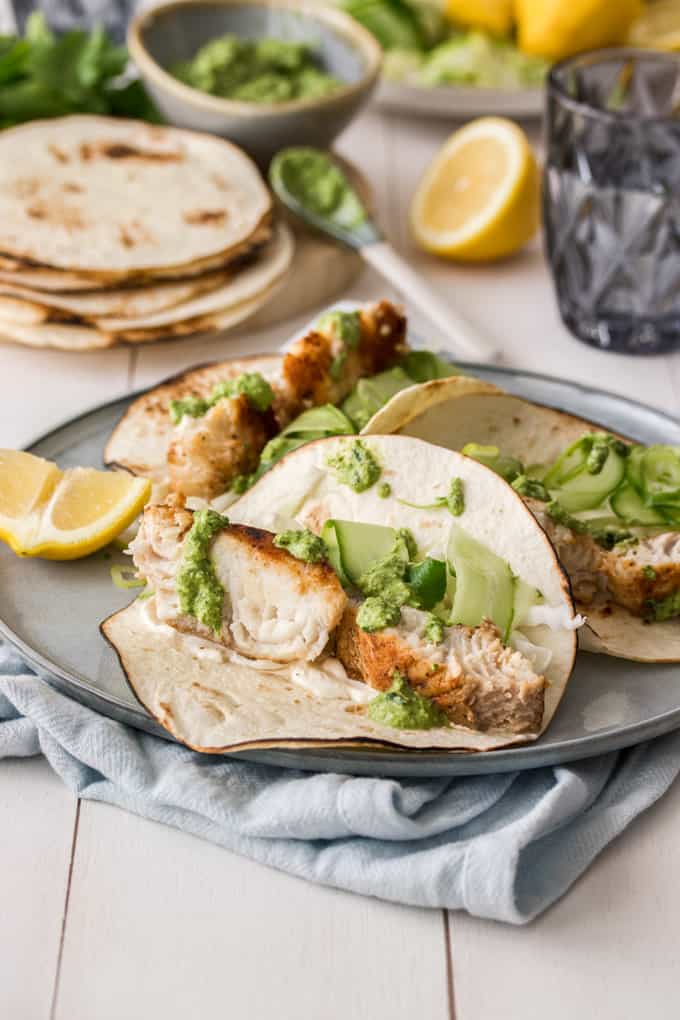 3 Fish Tacos on a grey plate with a lemon wedge
