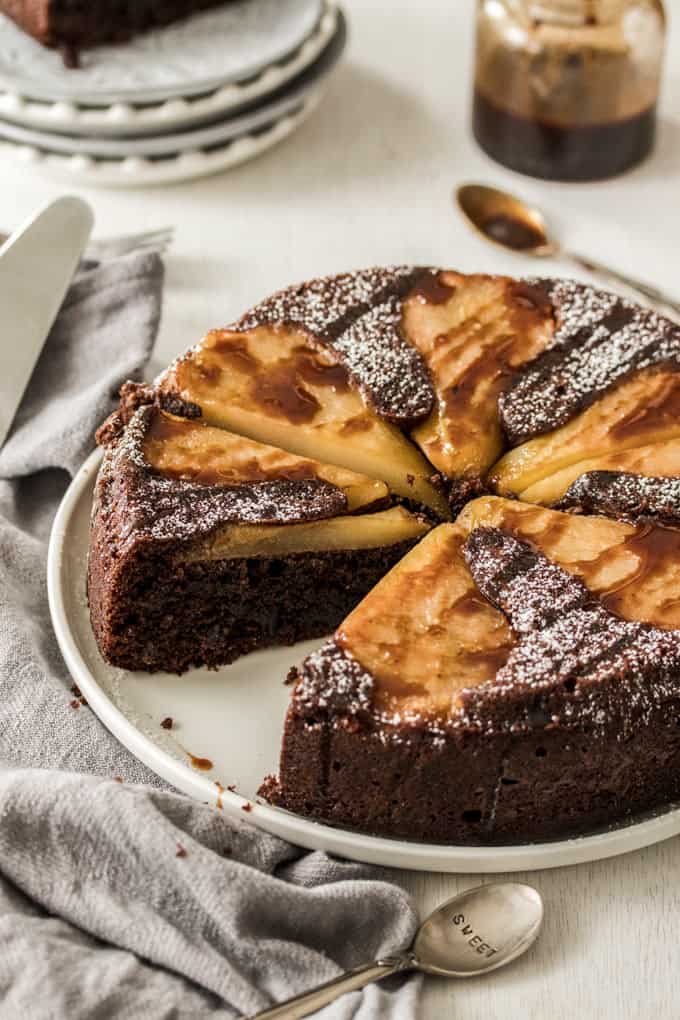 A Chocolate Pear Upside Down Cake with a slice missing, sitting on a white plate