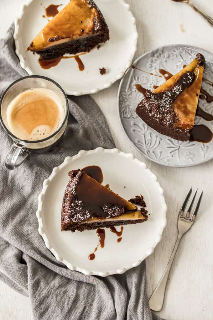 3 slices of Chocolate Pear Upside Down Cake on plates next to a glass of coffee