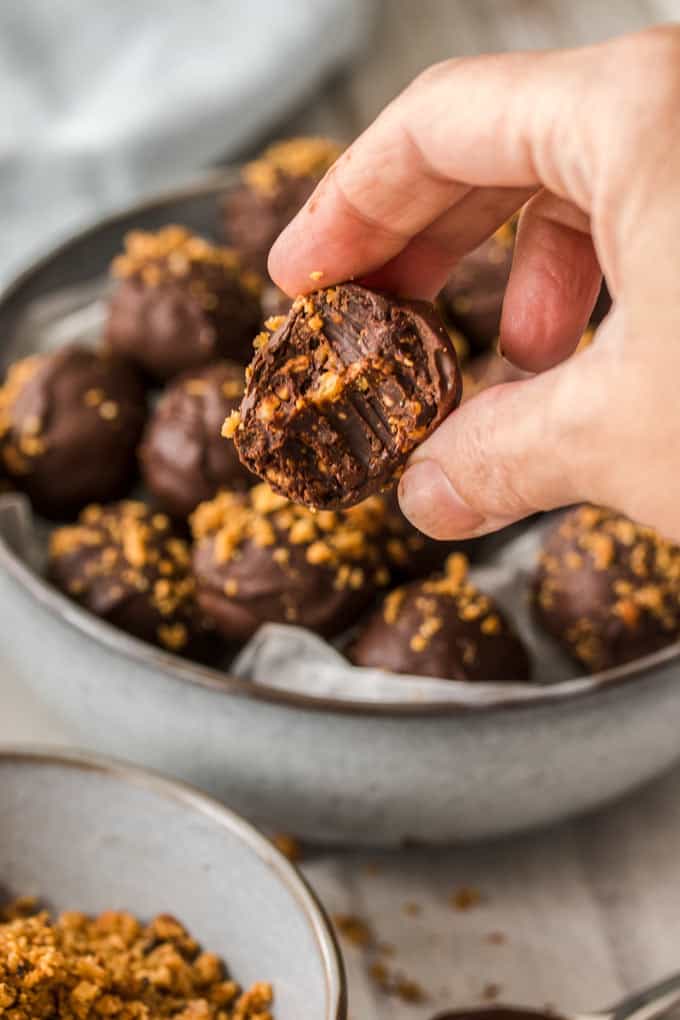 A Hazelnut Praline Chocolate Truffle with a bite taken out to show the inside texture