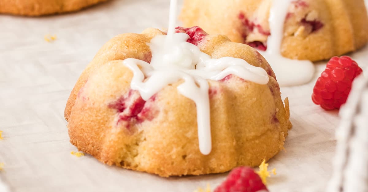 Closeup shot of white icing being drizzled on a Lemon Raspberry Mini Bundt Cake