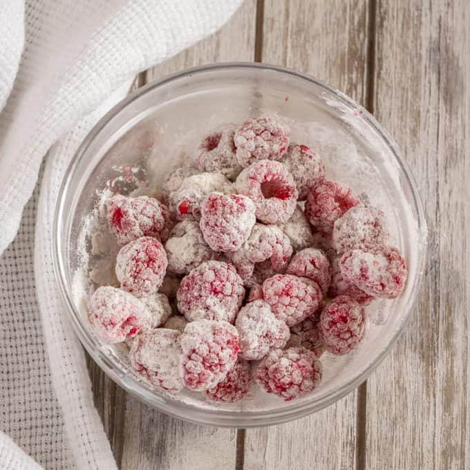 A bowl of raspberries coated in flour, ready to add to the batter