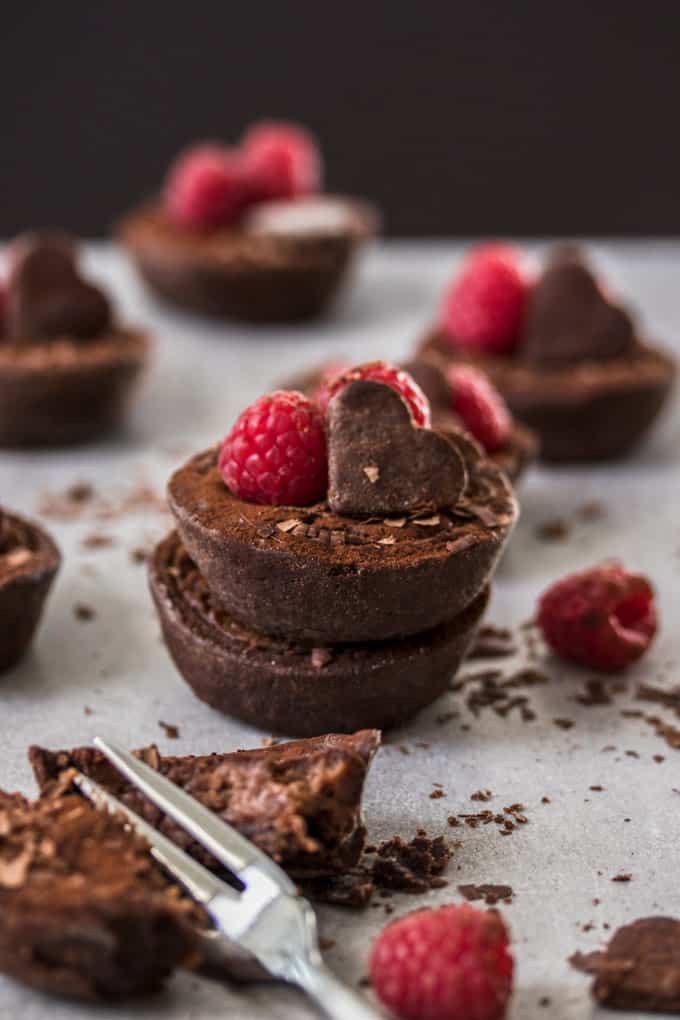 A stack of two mini chocolate tarts, one in the front is broken open with a fork