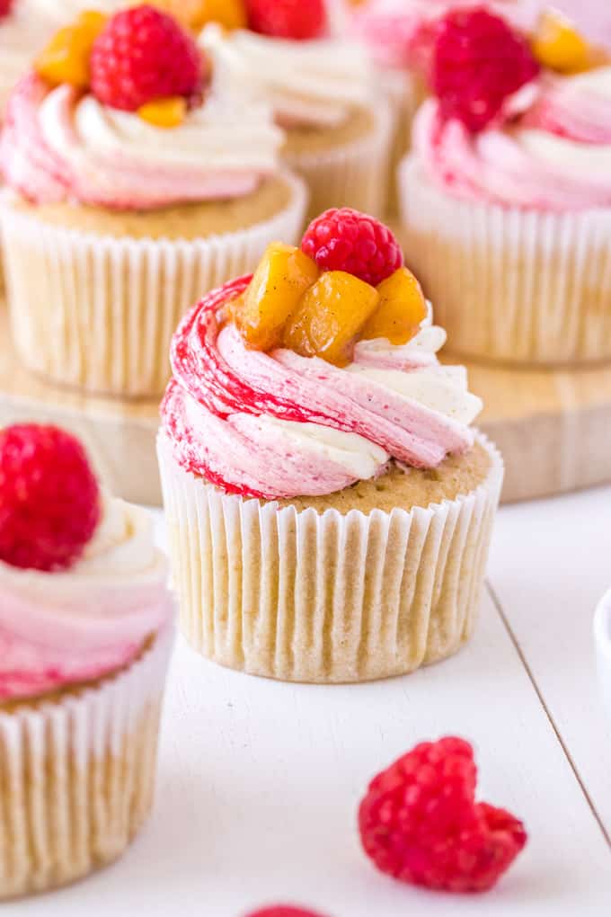 Closeup shot of a Peach Melba Cupcake, one in the foreground, and more in the background